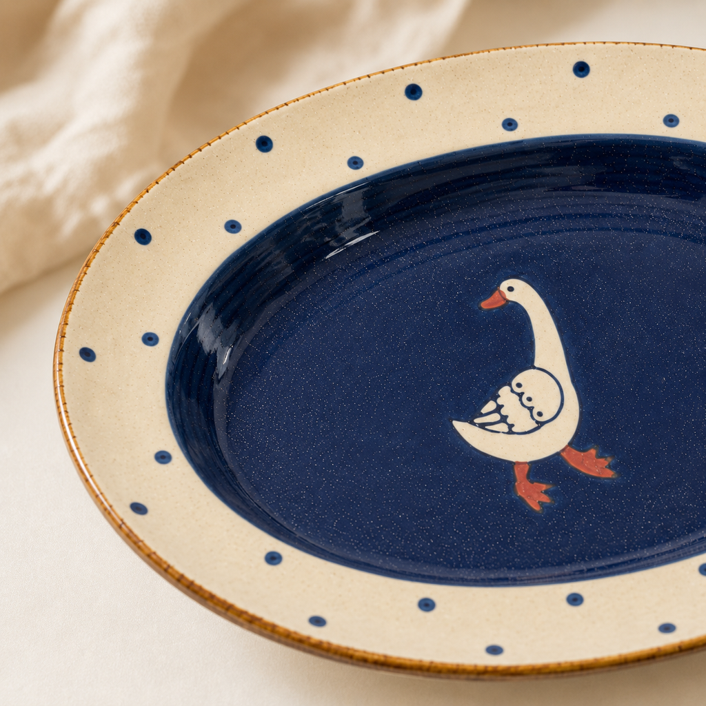 Close-up of goose ceramic plate with navy glaze, blue dots, and rustic brown rim